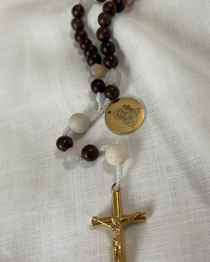 Close-up of a custom engraved gold Saint Joseph medal and a polished, tarnish-resistant gold crucifix attached to white hand-knotted cord.