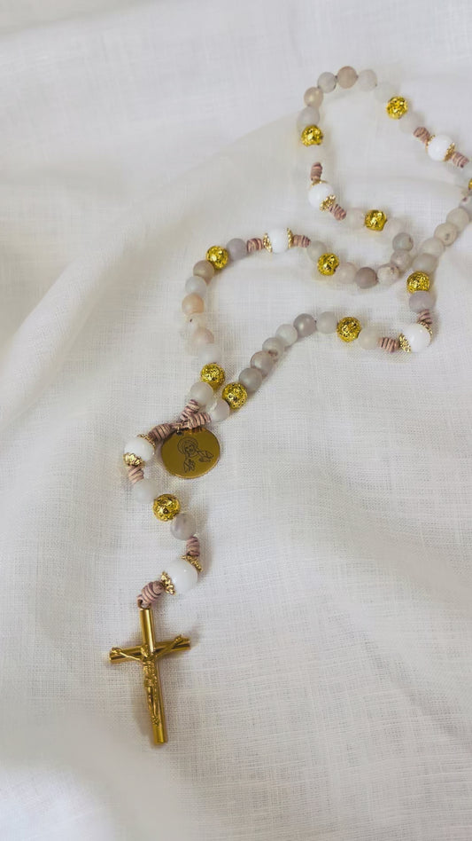 A slow vertical loop video showcasing the unique textures of gold lava stone, druzy, and white jade beads on a hand-knotted leather cord rosary.