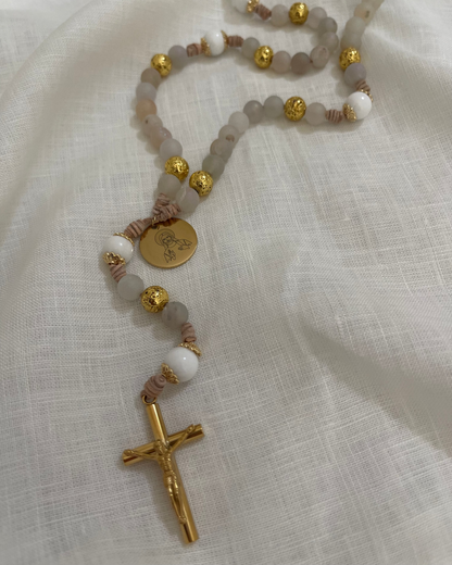 The Jesus Catholic rosary featuring white jade and gold lava stone beads laid flat on a neutral white linen background.